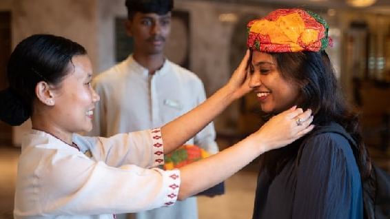 A woman welcoming a guest in a traditional Rajasthani way by placing a hat on her head - Kaldan Samudra Palace